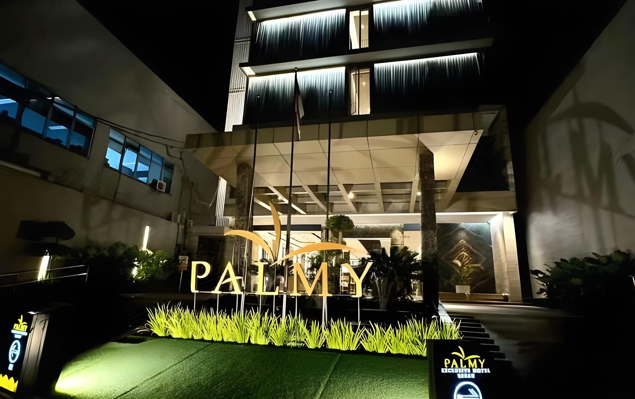A hotel entrance with a large illuminated sign reading 'PALMY EXCLUSIVE HOTEL.'