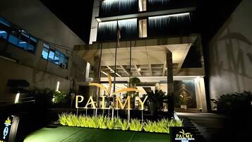 A hotel entrance with a large illuminated sign reading 'PALMY EXCLUSIVE HOTEL.'