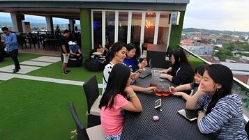 A rooftop terrace with a dining table, chairs, and a view of the cityscape.