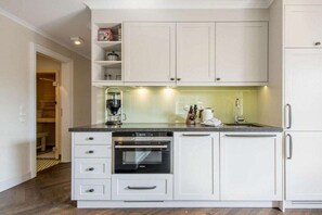 A compact kitchen with white cabinetry, a built-in oven, and a coffee maker. - Holiday apartment in Westerland with sauna (Westerland)