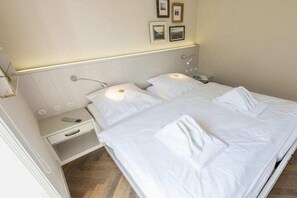 A hotel room with a bed, bedside table, and a wall-mounted lamp. - Holiday apartment in Westerland with sauna (Westerland)