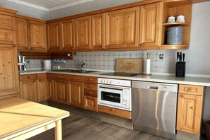 A kitchen with wooden cabinets, a stainless steel dishwasher, and a countertop with a coffee maker. - Holiday apartment with 1 bedroom (Norderney)