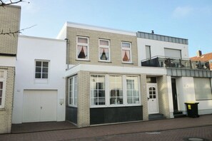 A two-story residential building with a garage, a balcony, and a trash bin. - Holiday apartment with 1 bedroom (Norderney)