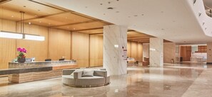 Et hotellobby med en receptionsdisk, et rundt siddeområde og en marmorkolonne.