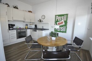 Eine moderne Küche mit weißen Schränken, einem Holzespeisetisch mit vier Stühlen und einer Persil-Werbeanzeige an der Wand.