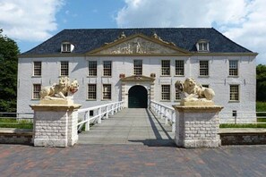 A stately building with a symmetrical facade, a central entrance, and two lion statues on either side. - Holiday bungalow Neßmersiel (Neßmersiel)