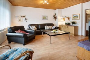 A living room with a sofa, a coffee table, and a wooden cabinet. - Holiday bungalow Neßmersiel (Neßmersiel)