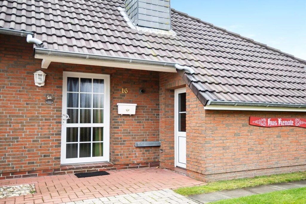A brick building with a tiled roof, a numbered door, and a sign on the wall.