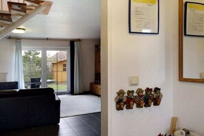 Une pièce avec un canapé, un escalier et un mur orné de diplômes et de peluches.