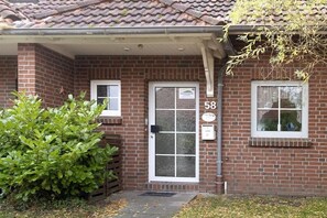 Un bâtiment en briques avec une porte numérotée, une petite fenêtre et une boîte aux lettres.