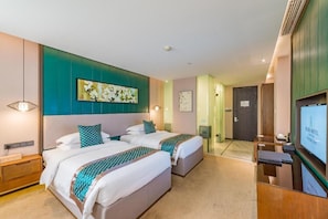 Quarto de hotel com duas camas, televisão e obras de arte nas paredes.