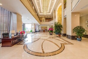 Um hall amplo com balcão de atendimento, área de estar e um padrão decorativo no chão.