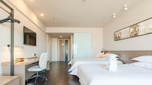 Quarto de hotel com escrivaninha, cadeira, duas camas e televisão de tela plana.