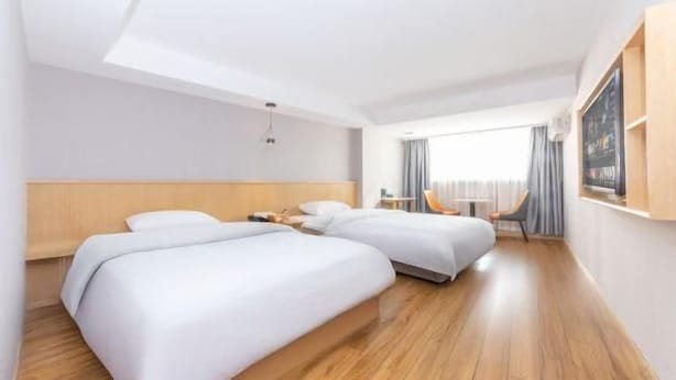 Quarto de hotel com duas camas, piso de madeira, uma janela grande e vista para o exterior.