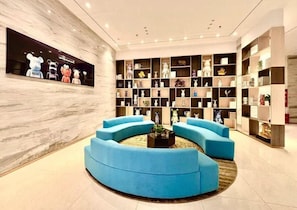 A modern lobby with a central seating area, a large wall-mounted display, and a collection of shelves with various items. - City Convenient Hotel (Hengyang)