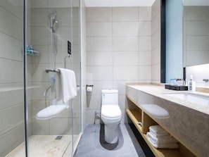 A modern bathroom with a glass shower enclosure, a toilet, and a vanity with a mirror. - City Convenient Hotel (Hengyang)