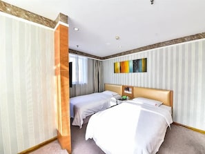 Habitació d'hotel amb dos llits, una paret decorativa de fusta, un quadre i una finestra amb cortines.