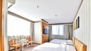 A hotel room with two beds, a sitting area with chairs and a table, and a television mounted on the wall. - Super 8 Quanzhou Anxi Longhu (Quanzhou)