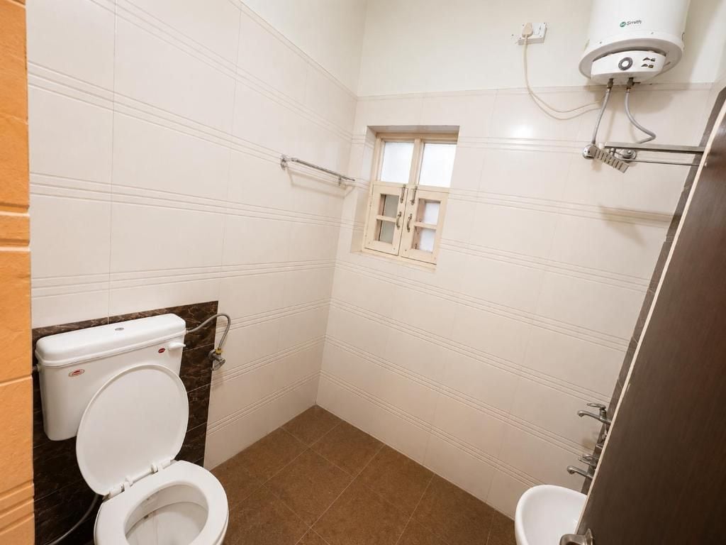 Un baño con inodoro, ventana y ducha.