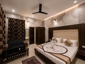 A hotel room with a bed, a sofa, a ceiling fan, and a patterned curtain. - Hotel Green Garden (Ludhiana)