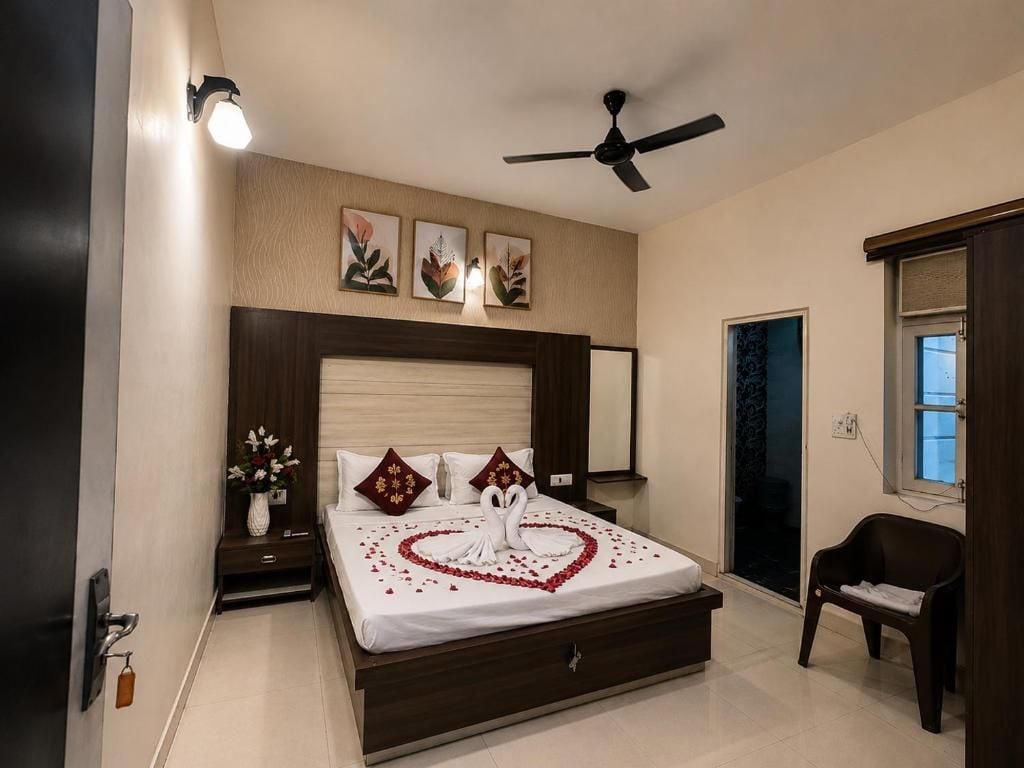 A hotel room with a bed, a ceiling fan, a nightstand with a vase of flowers, and a chair.