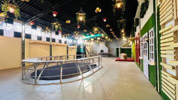 Amplio espacio interior con una zona de estar circular, una escalera y una pared verde con una puerta blanca.