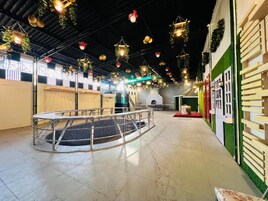 Amplio espacio interior con una zona de estar circular, una escalera y una pared verde con una puerta blanca.
