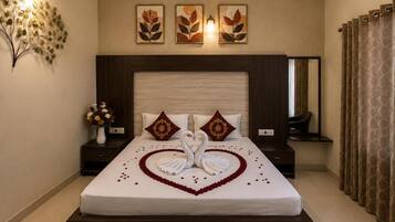 Una habitación de hotel con una cama grande, una mesita de noche con un florero y una obra de arte en la pared.