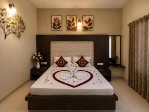 A hotel room with a large bed, a nightstand with a vase of flowers, and wall-mounted artwork.