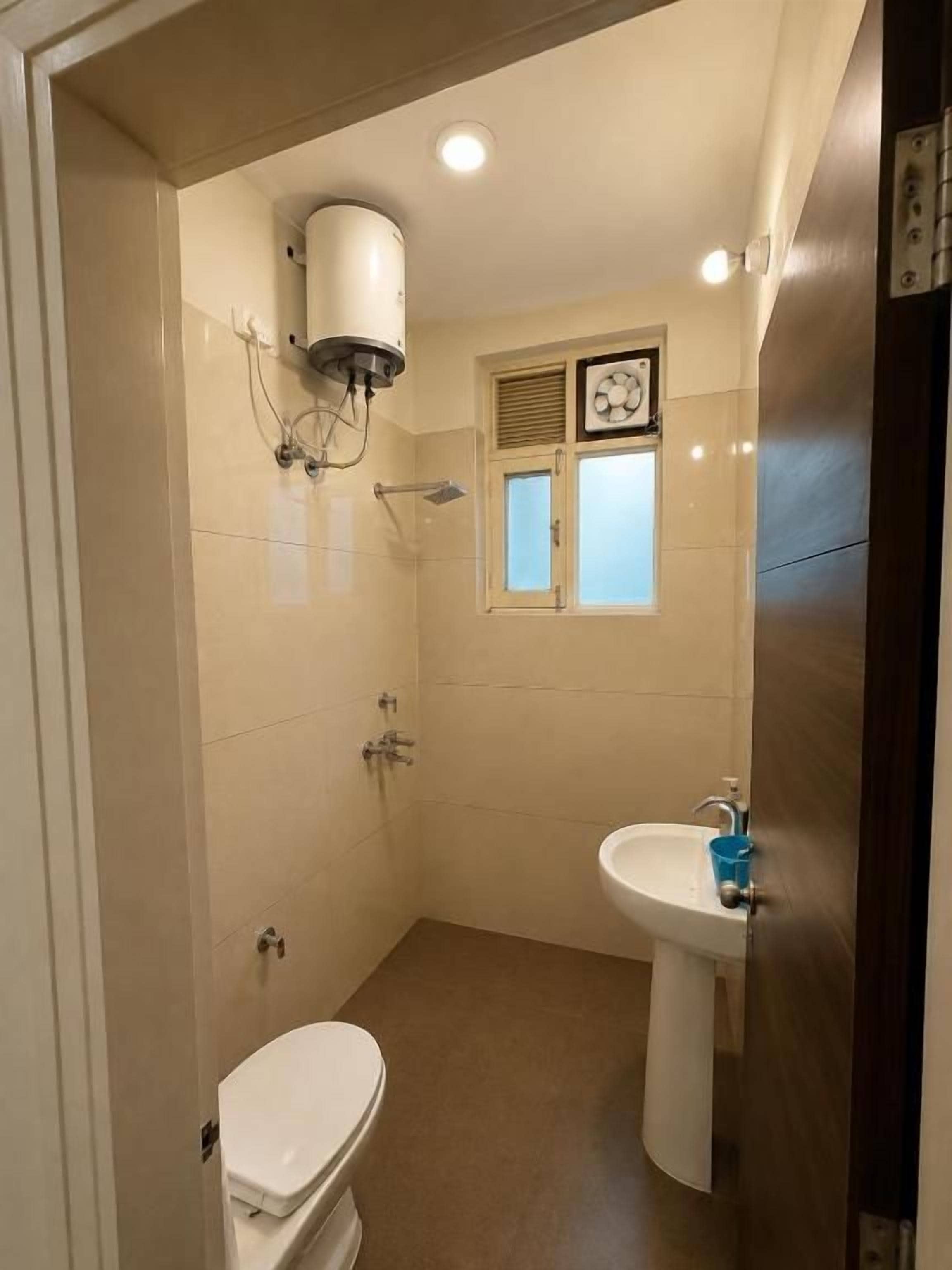 Un baño pequeño con inodoro, lavamanos, ventana y ducha.