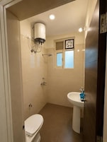 Un baño pequeño con inodoro, lavamanos, ventana y ducha.