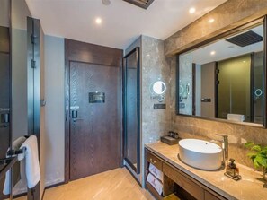 Un baño moderno con un espejo grande, un lavabo redondo y una puerta de madera.