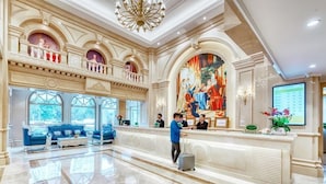 A spacious lobby with a marble floor, a reception desk, and a large painting. - Vienna International Hotel (Tianjin)