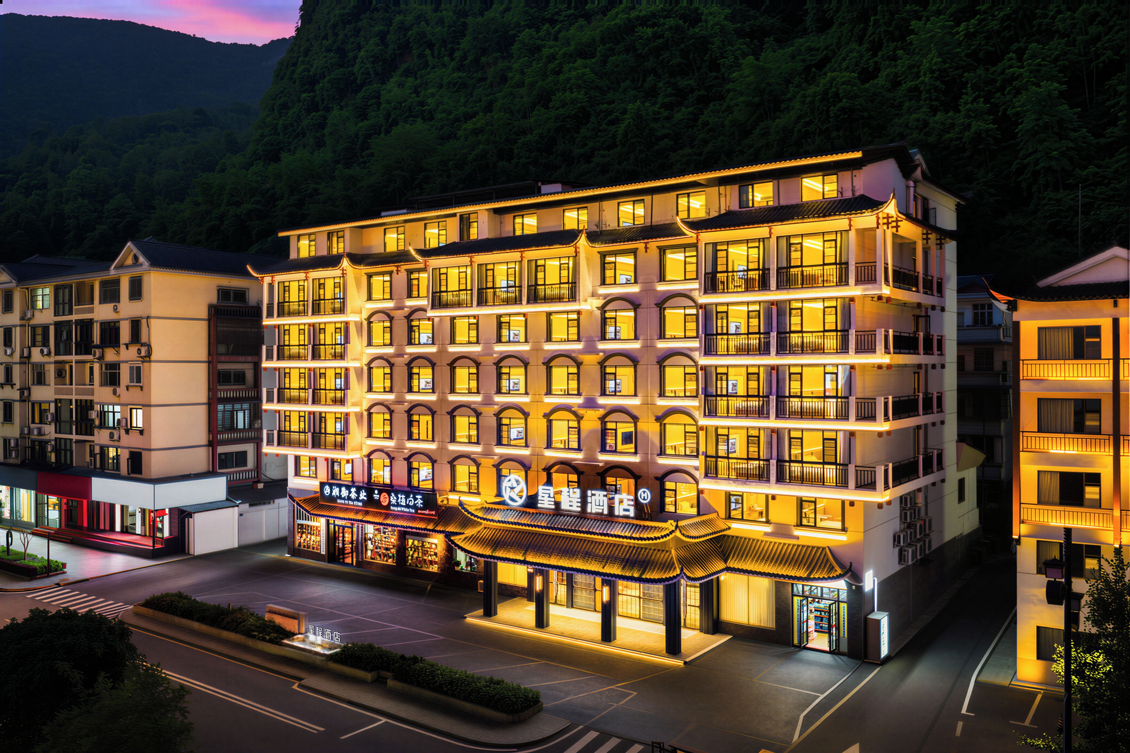 Un hôtel à plusieurs étages, de style architectural traditionnel, qui se distingue par son entrée imposante et son panneau indicateur.