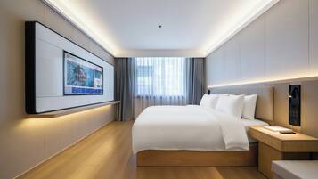 Una habitación de hotel con una cama grande, mesitas de noche, un televisor montado en la pared y vistas al exterior a través de la ventana.