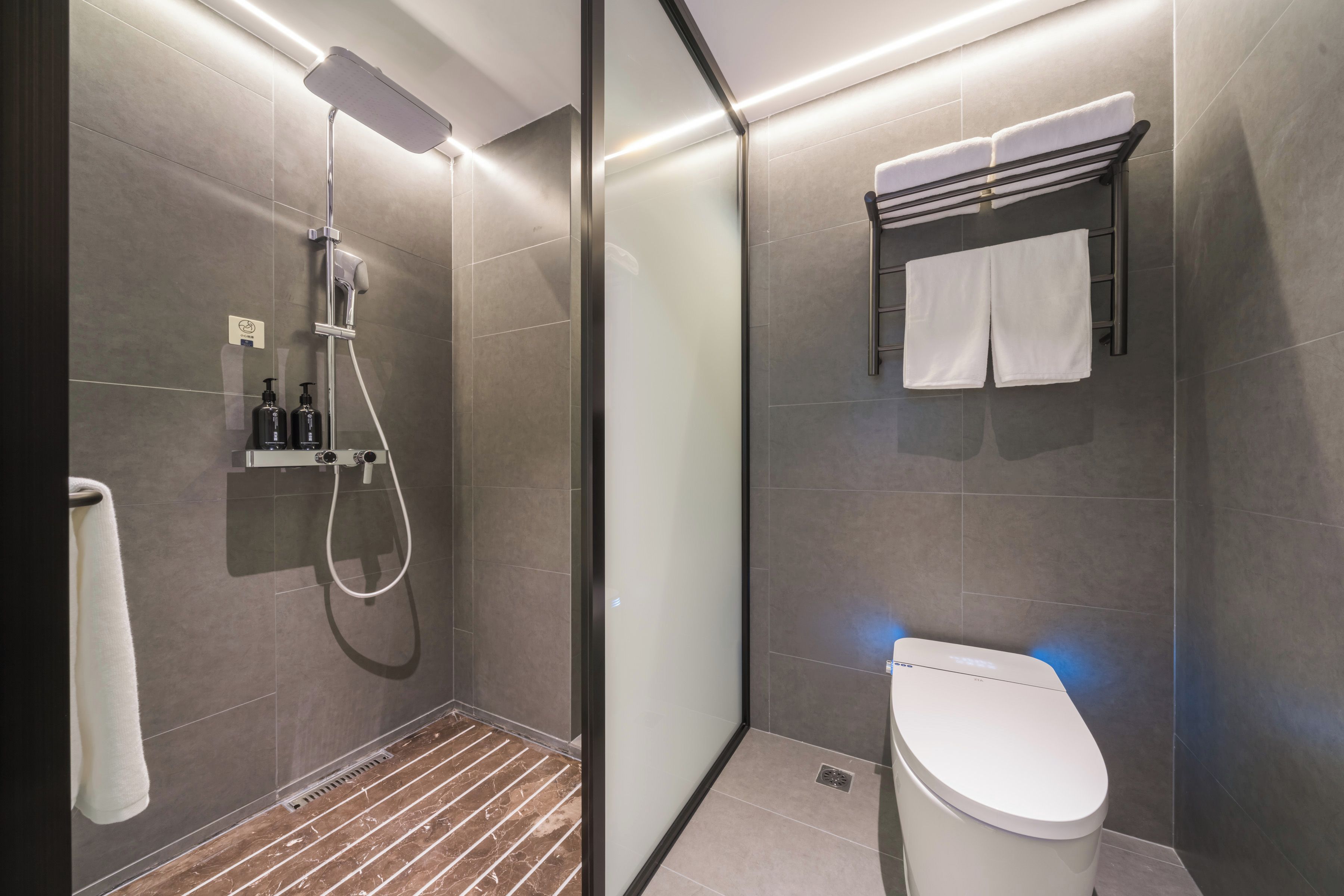 A modern bathroom with a shower, toilet, and towel rack.