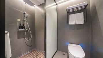 A modern bathroom with a shower, toilet, and towel rack.