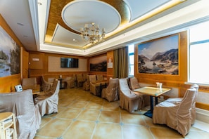 A restaurant with a chandelier, multiple tables, and chairs. - Vienna 3 Best Hotel (Wuhan)