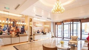 A hotel lobby with a reception desk, seating area, and large windows. - Vienna Hotel (Tianjin)
