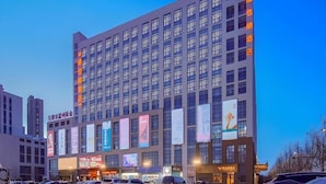 A multi-story hotel with a modern facade, large windows, and several banners advertising various services. - Vienna Hotel (Tianjin)