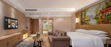 A hotel room with a bed, sofa, and a painting on the wall.