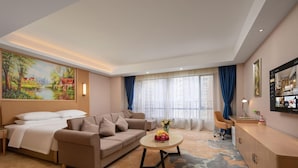 Et hotelværelse med seng, sofa, sofabord og et skrivebord med stol.