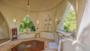 Um espaço de spa com piso de madeira, pia e janela com vista para o verde.