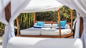 A bed with white linens and blue pillows, a wooden frame, and a canopy overhead. - Kilindi Zanzibar (Kendwa)