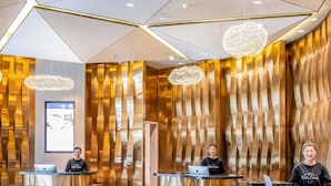 A hotel reception area with three reception desks, a modern interior design with metallic and wooden elements, and a large digital screen on the wall. - Atour Hotel Kunming International Trade Center (Kunming)