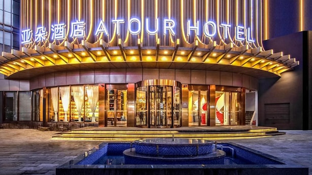 A hotel with a modern facade, illuminated signage, and a central courtyard with a fountain. - Atour Hotel Kunming International Trade Center (Kunming)