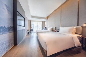 Ein modernes Hotelzimmer mit einem großen Bett, einem Schreibtisch und Blick auf die Stadt.