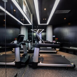 Ein Fitnessraum mit Laufbändern, Ergometer und einer Spiegelwand.