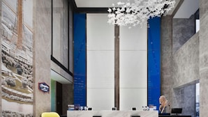 A modern reception area with a marble reception desk, a blue chair, and a yellow chair. - Hampton by Hilton Changchun High-tech Zone (Changchun)
