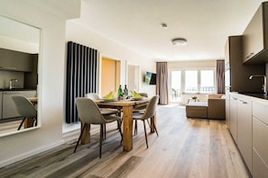 A modern hotel room with a dining area, kitchenette, and a balcony with a view. - Holiday apartment 705 (Winterberg)